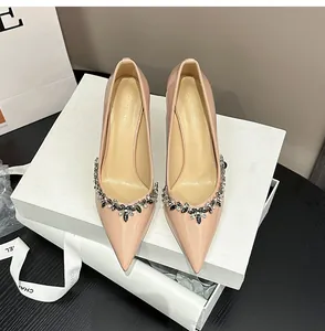 Detail of nude patent leather stiletto heels with sparkling rhinestone flower embellishment.
