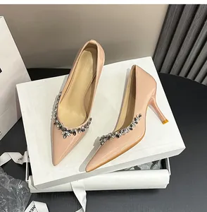 Macro detail of nude patent leather stiletto pumps featuring elegant crystal flower accents