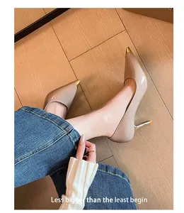 Detailaufnahme von eleganten nudefarbenen Stilettos mit goldenen metallischen Spitzen.