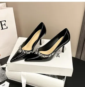Elegant black patent leather pointed toe heels with rhinestone trim on white boxes