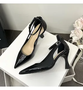 Close-up of black patent leather pointed-toe heels with ankle straps and side cutouts