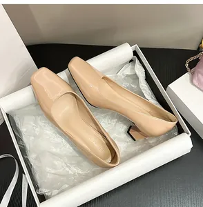 Primo piano di décolleté in vernice nude con punta quadrata in una scatola regalo bianca