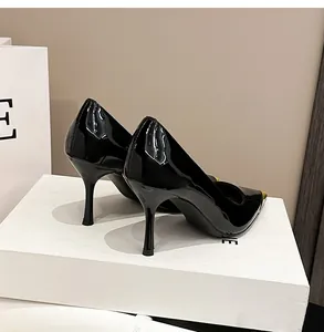 Elegante schwarze Lackleder-Stilettos mit goldener Metallkappe an der Spitze.