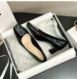 Dettaglio di décolleté in vernice nera con punta quadrata in una confezione regalo.