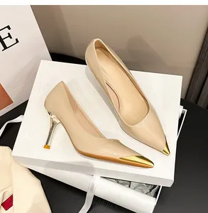 Detailansicht der beigen Lackleder-High-Heels mit goldener Metallkappe und Absatz.