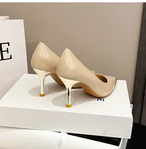 Detail von beigen Lackleder-Stilettos mit metallisch goldenen Absatzkappen