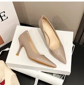 Elegante beigefarbene Lackleder-Stilettos mit spitzer Zehenpartie auf einer weißen Geschenkbox