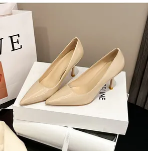 Elegante beige Lackleder-Pumps mit spitzer Zehenpartie auf weißen Geschenkkartons