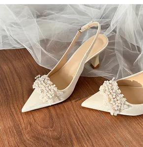Detail shot of ivory bridal heels featuring exquisite pearl and rhinestone clusters.