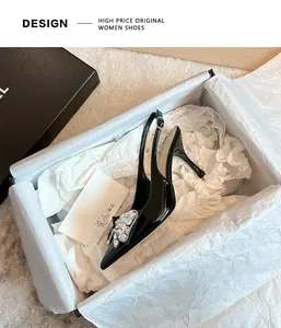 Dettaglio di décolleté in vernice nera con decorazione in strass nella scatola.