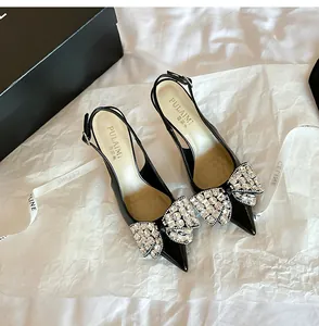 Dettaglio di décolleté slingback in vernice nera con fiocchi di strass brillanti