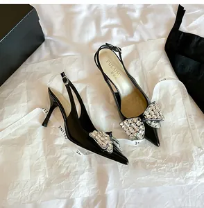Dettaglio di eleganti slingback in vernice nera con fiocco decorativo in strass