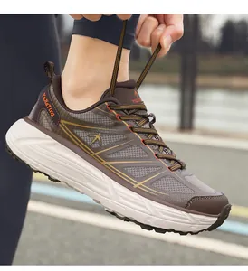 Macro view of brown breathable chunky sneakers with a hand tying laces in a park.