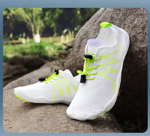 Close-up of breathable white wading shoes featuring neon green accents in a natural setting