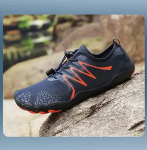 Side view of a breathable blue water shoe with orange accents on a natural rock surface.