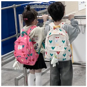 Two children wearing cute heart-patterned mini backpacks in a casual lifestyle setting