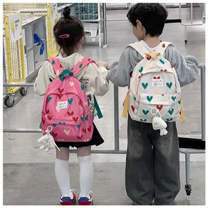 Rear view of two children wearing cute heart-patterned backpacks in pink and off-white colors.