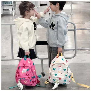 Lifestyle view of two children showcasing pink and white heart-patterned backpacks
