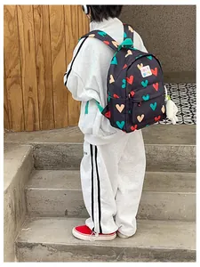 Cute toddler backpack with colorful heart patterns on black fabric worn by a child.