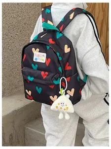 Back view of a cute black backpack with colorful heart patterns and a plush charm
