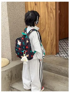 Detailed shot of a child wearing a black backpack with colorful heart prints and charm