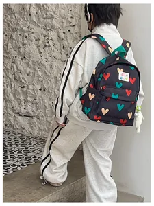 Detail shot of a cute black backpack with colorful heart patterns worn by a child.