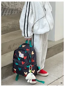 Cute children's backpack with heart pattern and plush charm shown on a child model outdoors