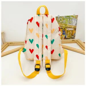Back view of a cute cream children's backpack with colorful heart patterns and yellow straps
