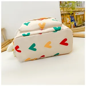 Detailed bottom view of a cute cream-colored kids backpack with vibrant heart print patterns