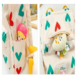 Close-up detail of a cream children's backpack featuring vibrant red and teal heart patterns