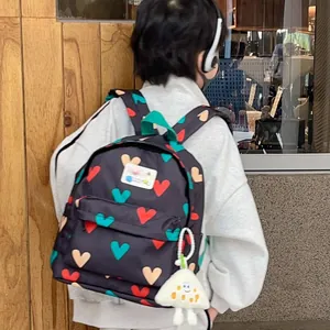 Cute black children's backpack with colorful heart patterns and white plush toy keychain