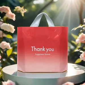 Rote und rosa plastische Geschenktüte mit Thank You Aufdruck im sonnigen Garten