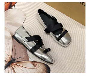 Detail of silver ballet flat shoes with black ribbon bow and criss-cross straps