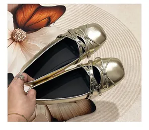 Detailed macro view of metallic gold Mary Jane ballet flats with bow and eyelet cross straps.