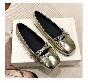 Detail showing gold Mary Jane flats with cross strap buckles and bow decoration.