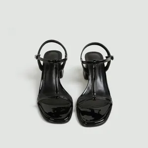 Vooraanzicht van zwarte laklederen sandalen met blokhak, T-bandje en enkelgesp.