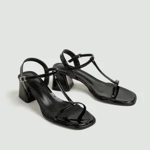 Detailopname van zwarte laksandalen met T-bandje, blokhak en een vierkante neus