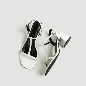 Gedetailleerd bovenaanzicht van witte T-strap sandalen met blokhak en zwarte zool