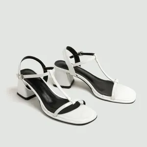 Zijaanzicht van elegante witte T-strap sandalen met blokhak en vierkante open neus
