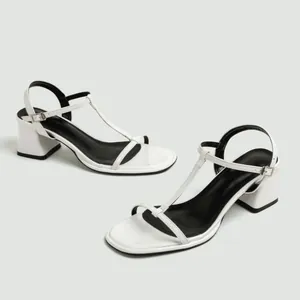 Gedetailleerd zijaanzicht van witte T-strap sandalen met blokhak en open teenontwerp