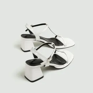 Detail van elegante witte sandalen met blokhak, enkelbandjes en een open teenontwerp