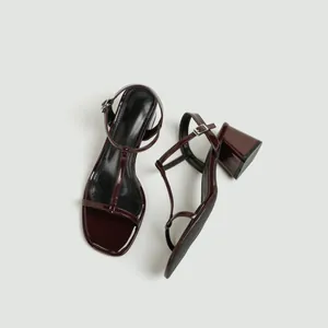 Gedetailleerd overzicht van bordeauxrode lakleren T-strap sandalen met blokhak.