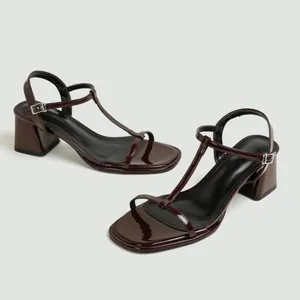 Gedetailleerd zijaanzicht van elegante donkerbruine laksandalen met blokhak en T-band