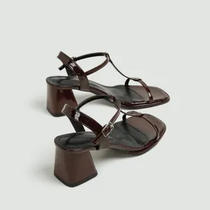 Detailweergave van de donkerbruine lakleren sandalen met blokhak en enkelbandje voor dames