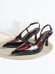 Detalle de elegantes zapatos de tacón de aguja en charol burdeos y negro con punta fina.