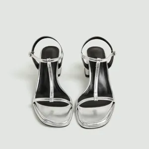 Vooraanzicht van zilveren sandalen met blokhak, elegant T-bandje en gespsluiting.