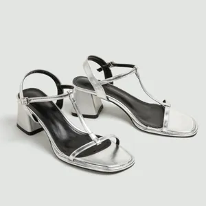 Detail van zilveren T-strap sandalen met een dikke blokhak en een stijlvolle vierkante neus.