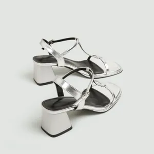 Gedetailleerd zijaanzicht van elegante zilveren sandalen met blokhak en een enkelbandje