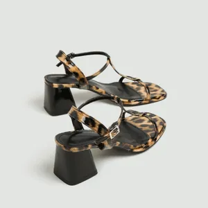 Gedetailleerd zijaanzicht van dames sandalen met blokhak en luipaardprint detail