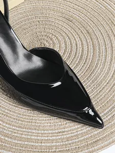 Primer plano de elegantes zapatos de tacón en charol negro con punta fina y brillo